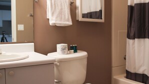 Baño con inodoro, lavabo, espejo y cortina de ducha.