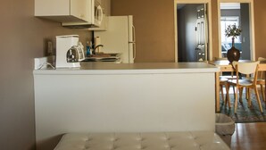 Una cocina moderna con armarios blancos, horno empotrado y comedor con banco y sillas.