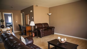 A living room with a brown leather sofa, a dark wooden coffee table, and a lamp.