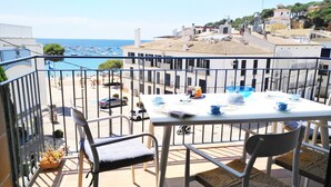 Un balcón con una mesa para dos, con vista a la playa y al mar.