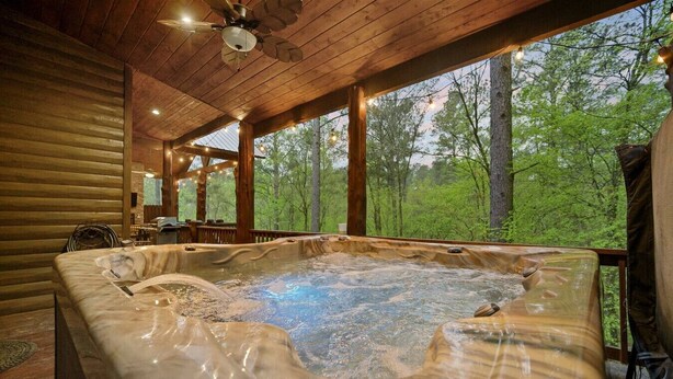 Un jacuzzi en una cabaña de madera con vista a un bosque.