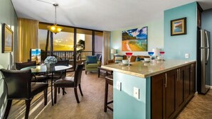 Une chambre d’hôtel compacte comprenant un coin repas, une kitchenette et une grande fenêtre donnant sur la plage.