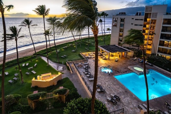 A hotel with a pool, lounge chairs, and a view of the beach and ocean.