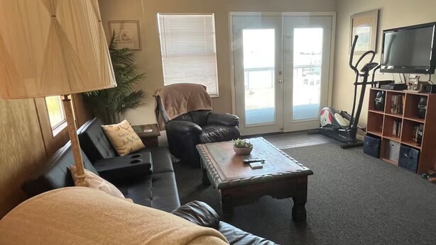 Una sala de estar con sofá, mesa de centro, televisor y caminadora.
