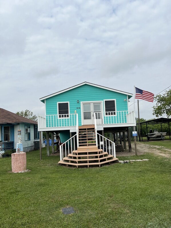 A turquoise house with a white porch and a wooden staircase leading to a door. - Remote Bay View Home near tranquil Carancahua Bay (Port Lavaca)