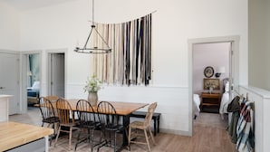 A modern kitchen with a wooden dining table, black chairs, and a hanging light fixture. - 3-East: Luxe 3BR in Downtown Nashville, IN w/ Rooftop Patio (Nashville)