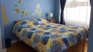 Une chambre à coucher avec un lit, une table de chevet, une lampe et une fenêtre avec des rideaux.