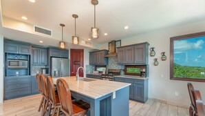 A modern kitchen with a central island, built-in appliances, and pendant lighting. - Sweeping panoramic views of the reef  (Bay Islands Department)