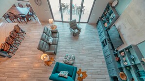 A spacious living area with a large dining table, comfortable seating, and a view through large windows. - Sweeping panoramic views of the reef  (Bay Islands Department)