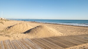 A sandy beach with a wooden boardwalk leading to the water. - PINK SEAFRONT (Torrevieja)