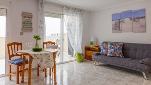 A dining area with a table, chairs, and a sofa. - PINK SEAFRONT (Torrevieja)