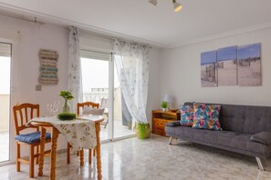 A dining area with a table, chairs, and a sofa. - PINK SEAFRONT (Torrevieja)