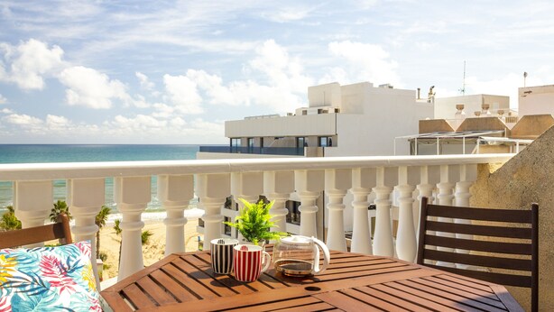 A terrace with a table, chairs, and a view of the beach and ocean. - PINK SEAFRONT (Torrevieja)