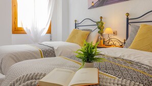 A hotel room with two beds, a potted plant, and a painting on the wall. - PINK SEAFRONT (Torrevieja)