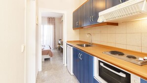 Una cocina compacta con armarios azul oscuro, encimera de madera, horno empotrado y un lavabo.