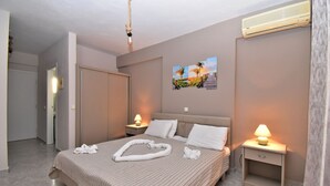 Habitación de hotel con cama, mesitas de noche, aire acondicionado de pared y una puerta.