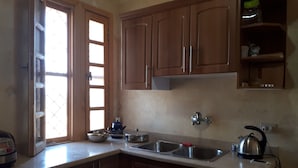A kitchen with wooden cabinets, a double sink, and a window with blinds. - Beautiful villa with private beach on the Red sea (Бур-Сафага)