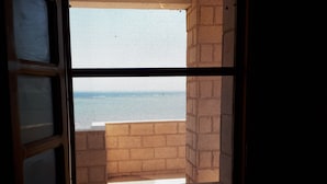 A window with a view of the sea and a building in the background. - Beautiful villa with private beach on the Red sea (Бур-Сафага)