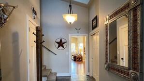 Un pasillo con decoración de estrellas, una escalera de madera, un tapete y un espejo con marco decorativo.