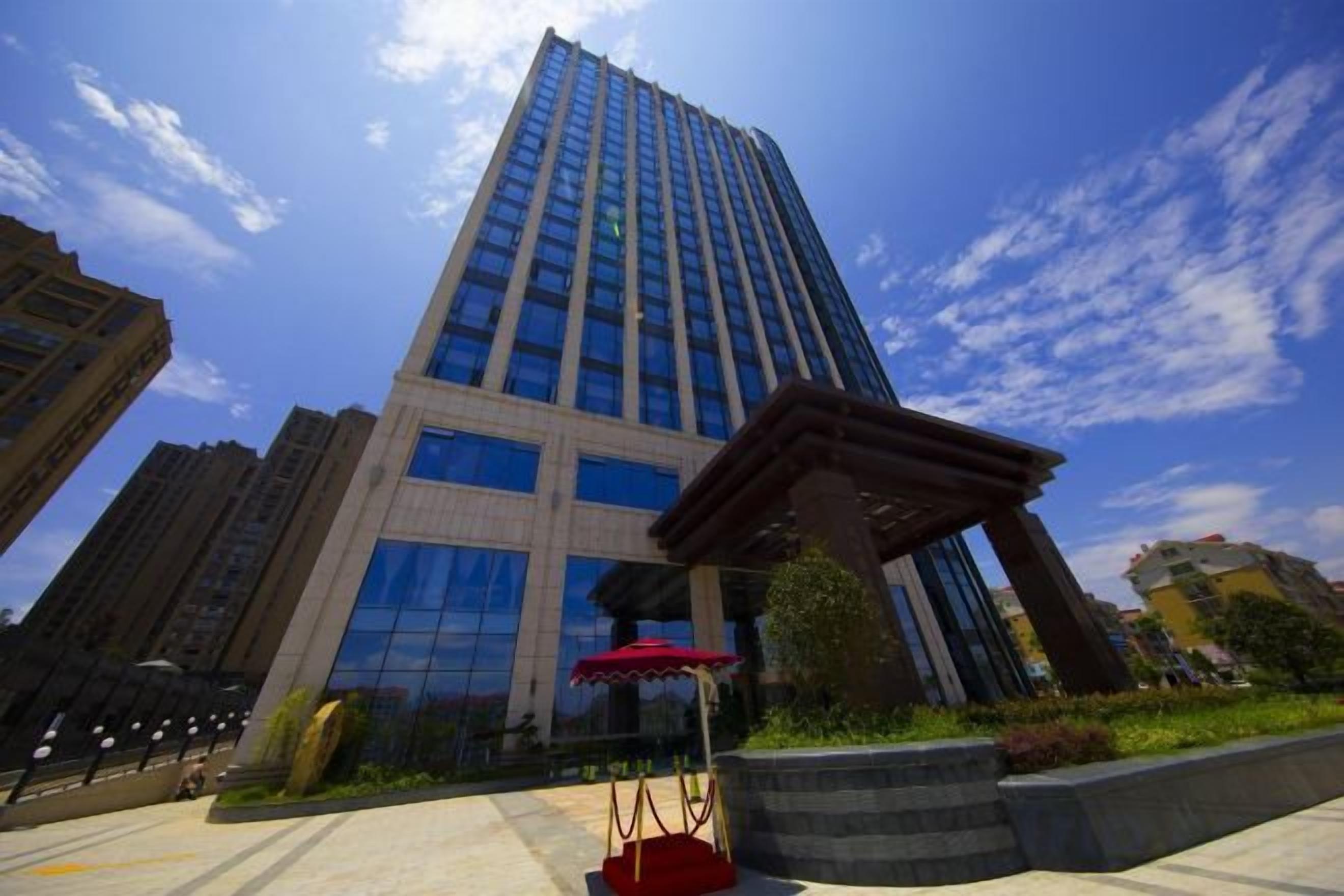 A tall building with a modern design, surrounded by a well-maintained plaza with a red canopy structure.