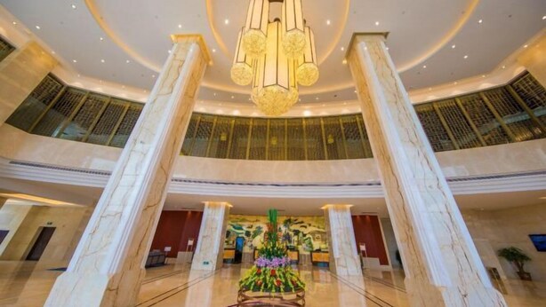 A spacious lobby with marble columns, a central floral arrangement, and a modern chandelier. - Wen Gong Hotel (Youxi)