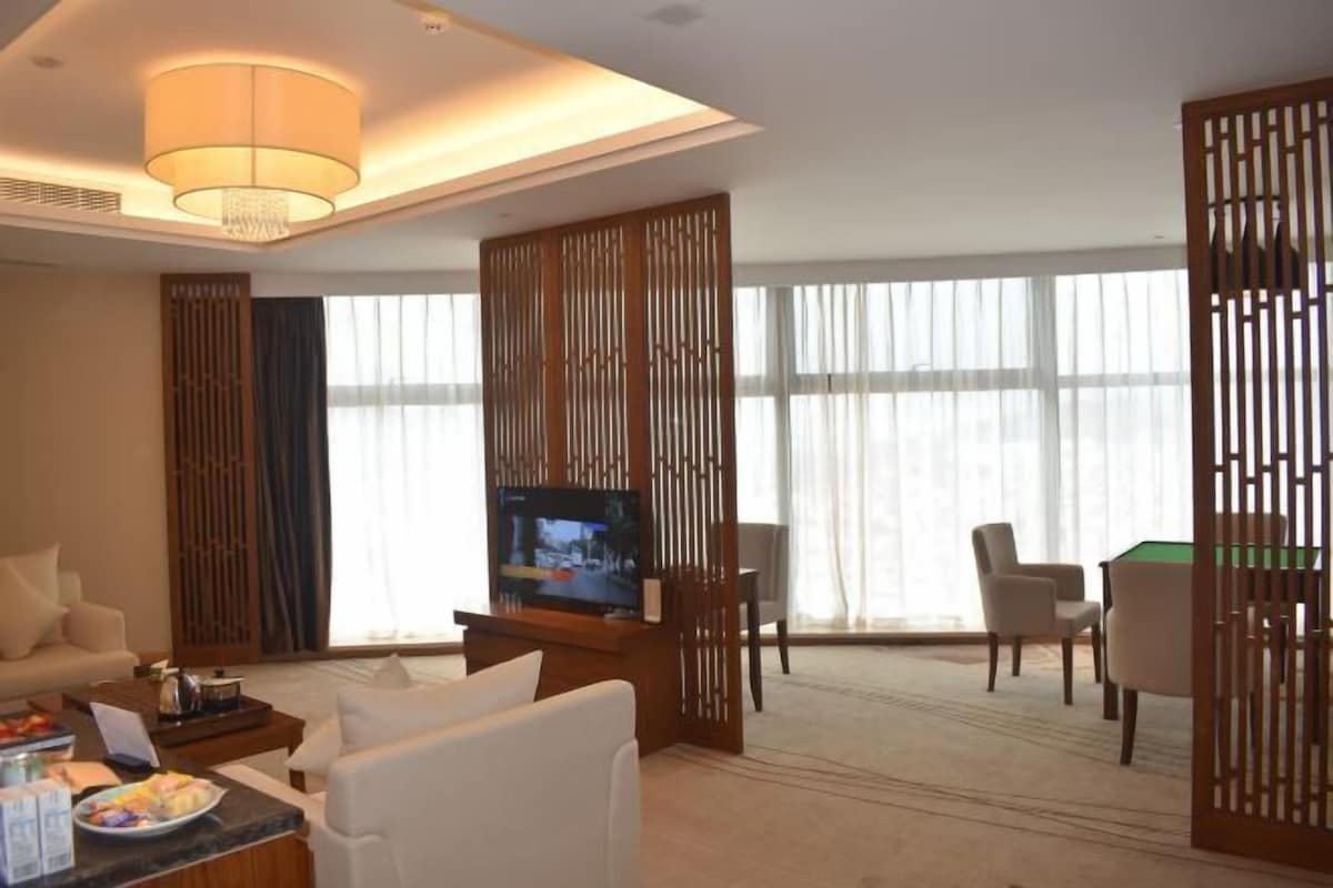 Habitación de hotel con televisión, sofá, mesa de comedor y mesa de billar.