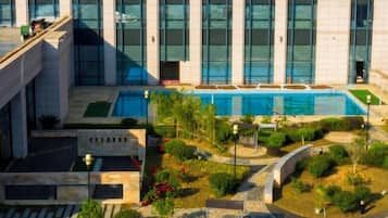 Un edificio moderno con piscina, rodeado de jardines ajardinados y senderos.