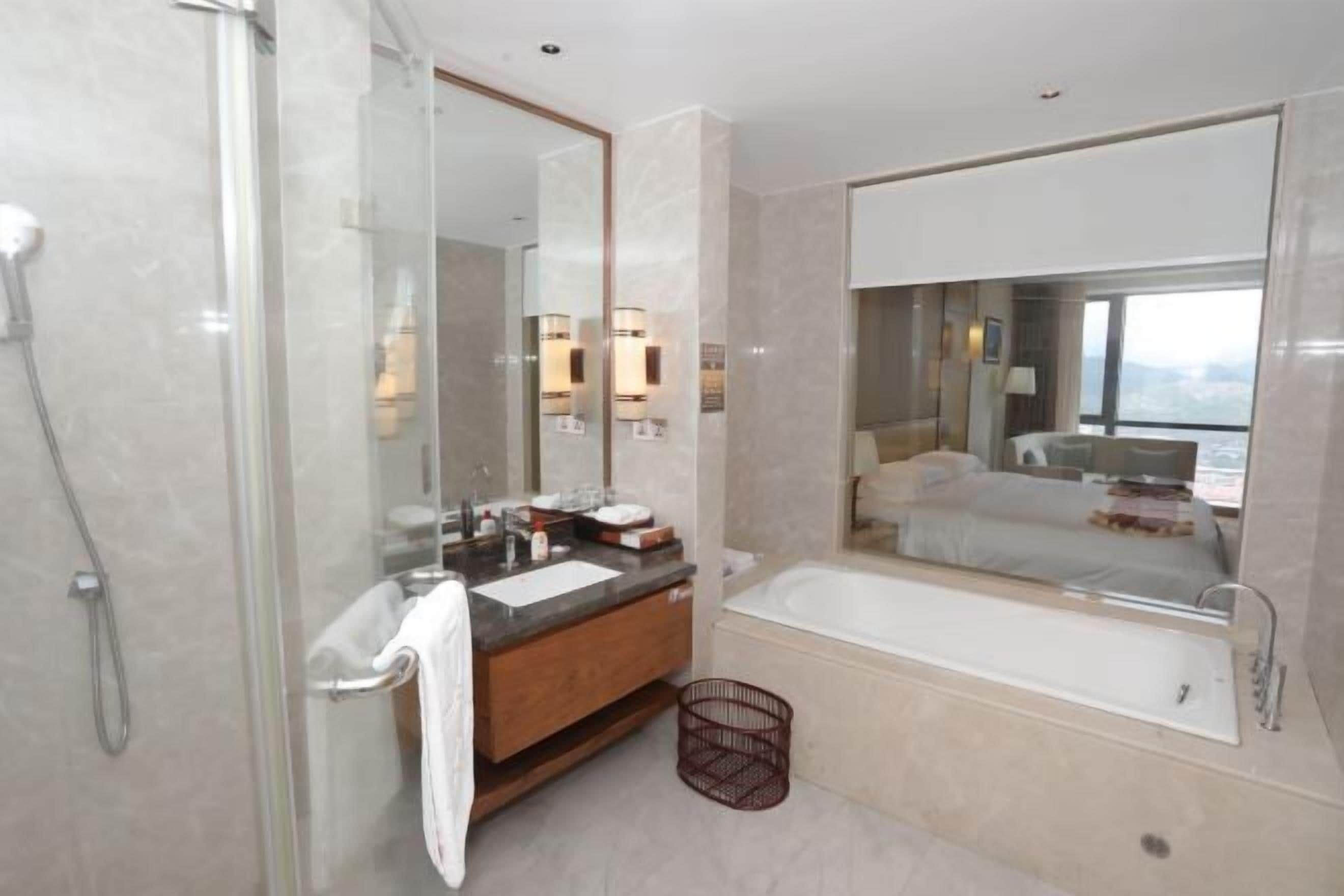 Ein modernes Badezimmer mit einer Duschkabine, einem Holzbadezimmer-Möbelstück, einem großen Spiegel und einer Badewanne.