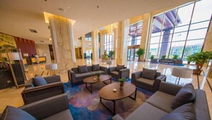 A spacious lobby with modern furniture, large windows, and a marble reception desk. - Wen Gong Hotel (Youxi)