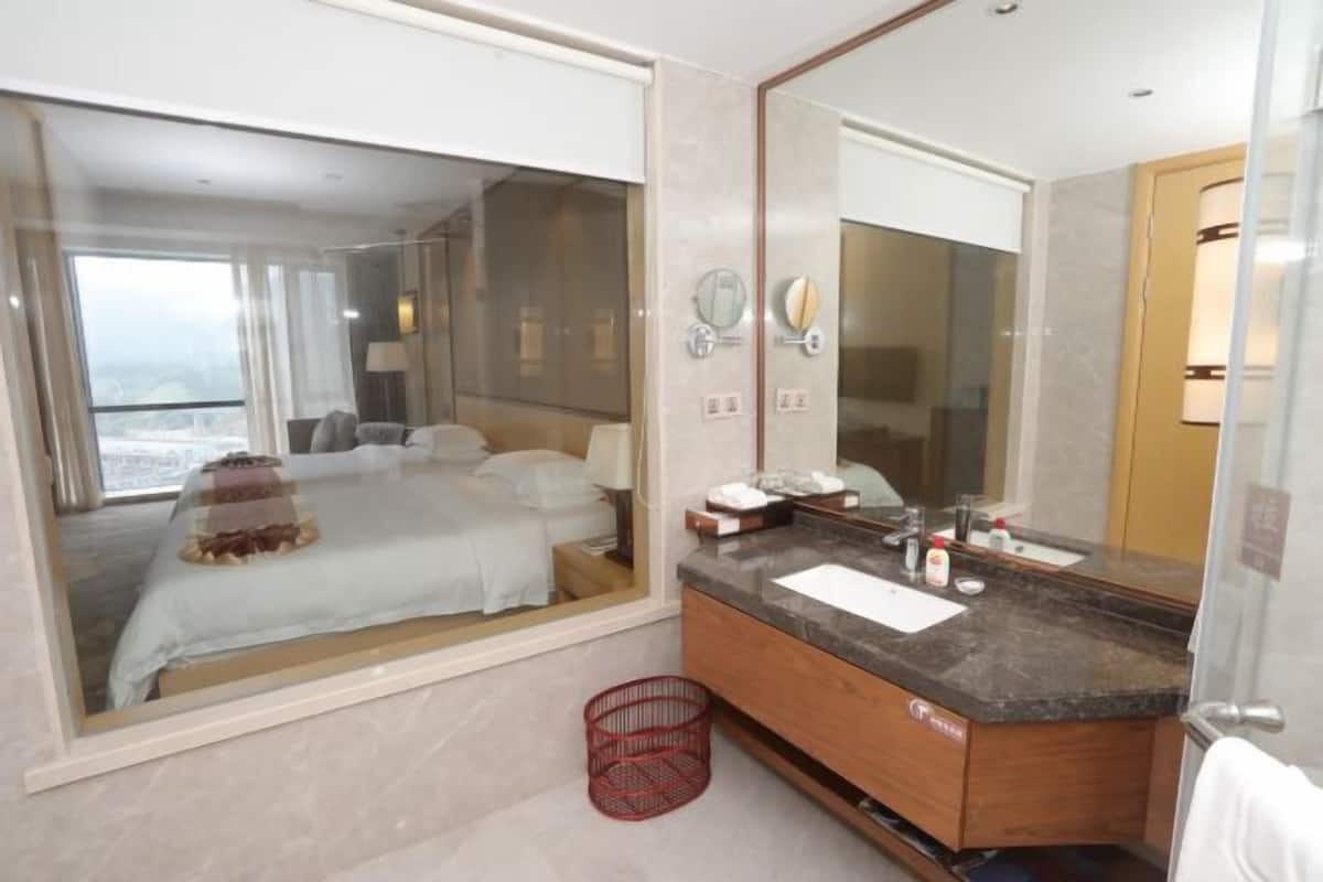 A modern hotel room with a large bed, a bathroom with a marble countertop, and a large mirror.