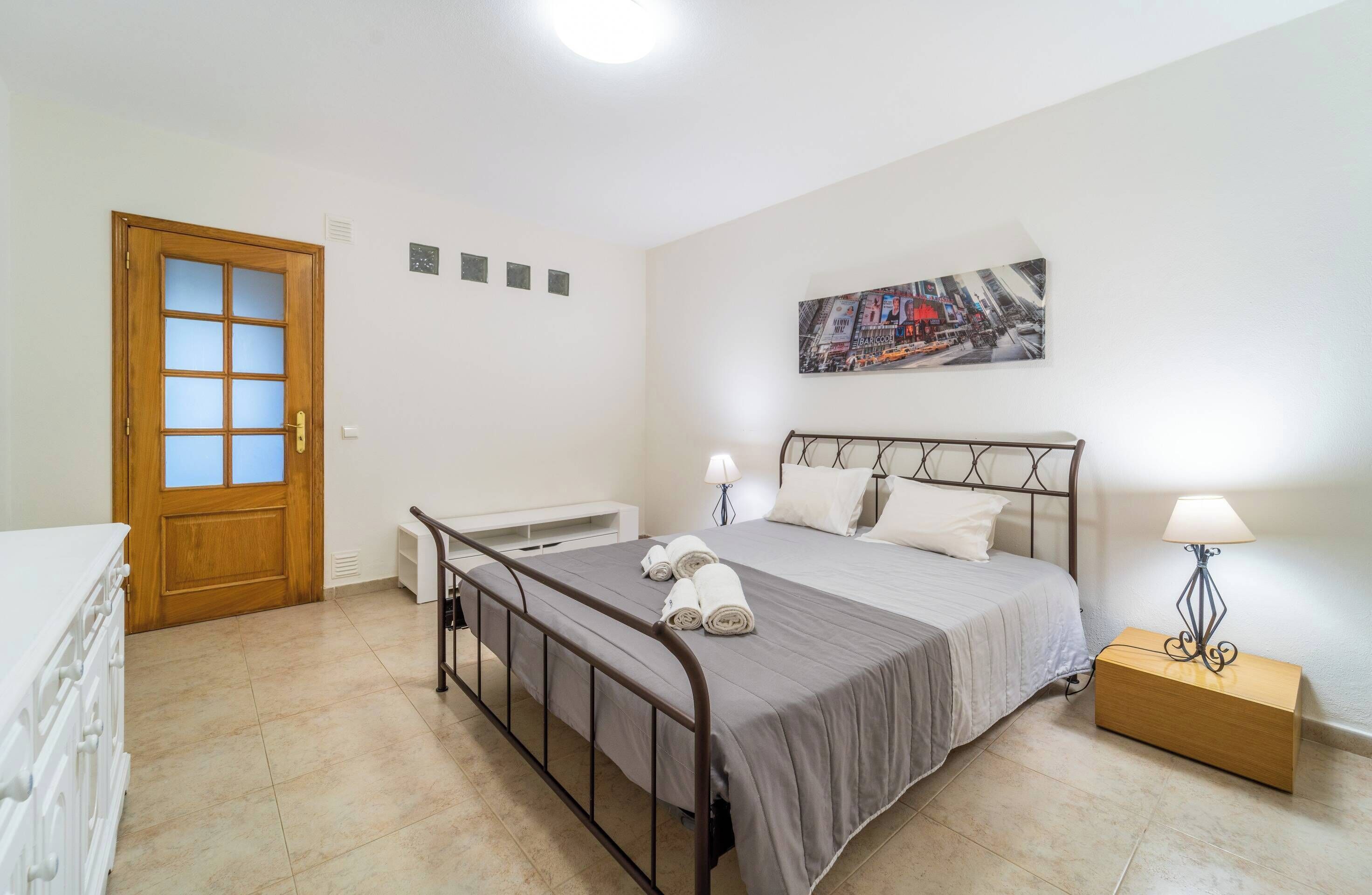 Une chambre à coucher avec un lit, des lampes de chevet, une table de chevet en bois et une porte.