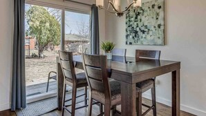 A dining area with a wooden table and chairs, a chandelier, and a large abstract painting on the wall. - Luxury Modern 3BR - Private Primary Suite! (Oklahoma City)