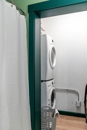 A laundry room with a washing machine, a drying rack, and a basket.