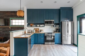 A modern kitchen with blue cabinets, stainless steel appliances, and a wooden island.