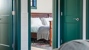 A room with a bed, a window with blinds, and a green door.