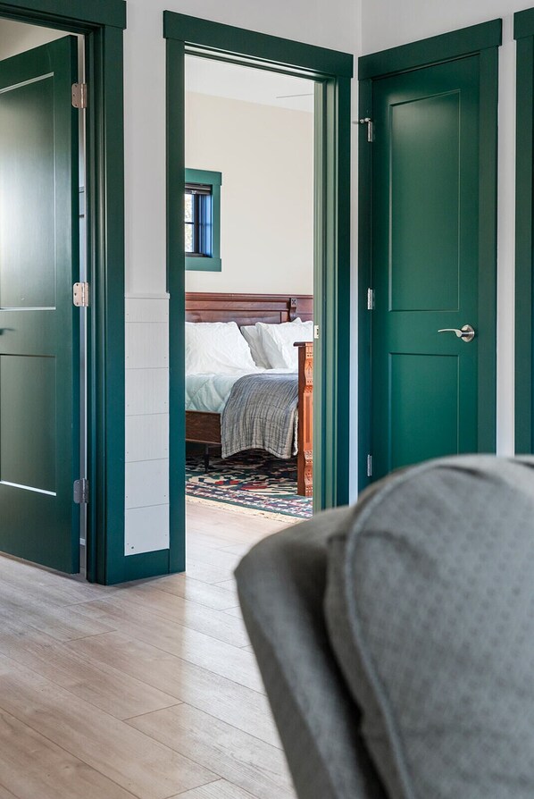 A room with a bed, a window with blinds, and a green door.