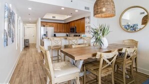 A spacious kitchen with wooden cabinets, a central island, and a hanging pendant light. - Updated Beachfront Condo w/private balcony and Pool (Gulf Shores)