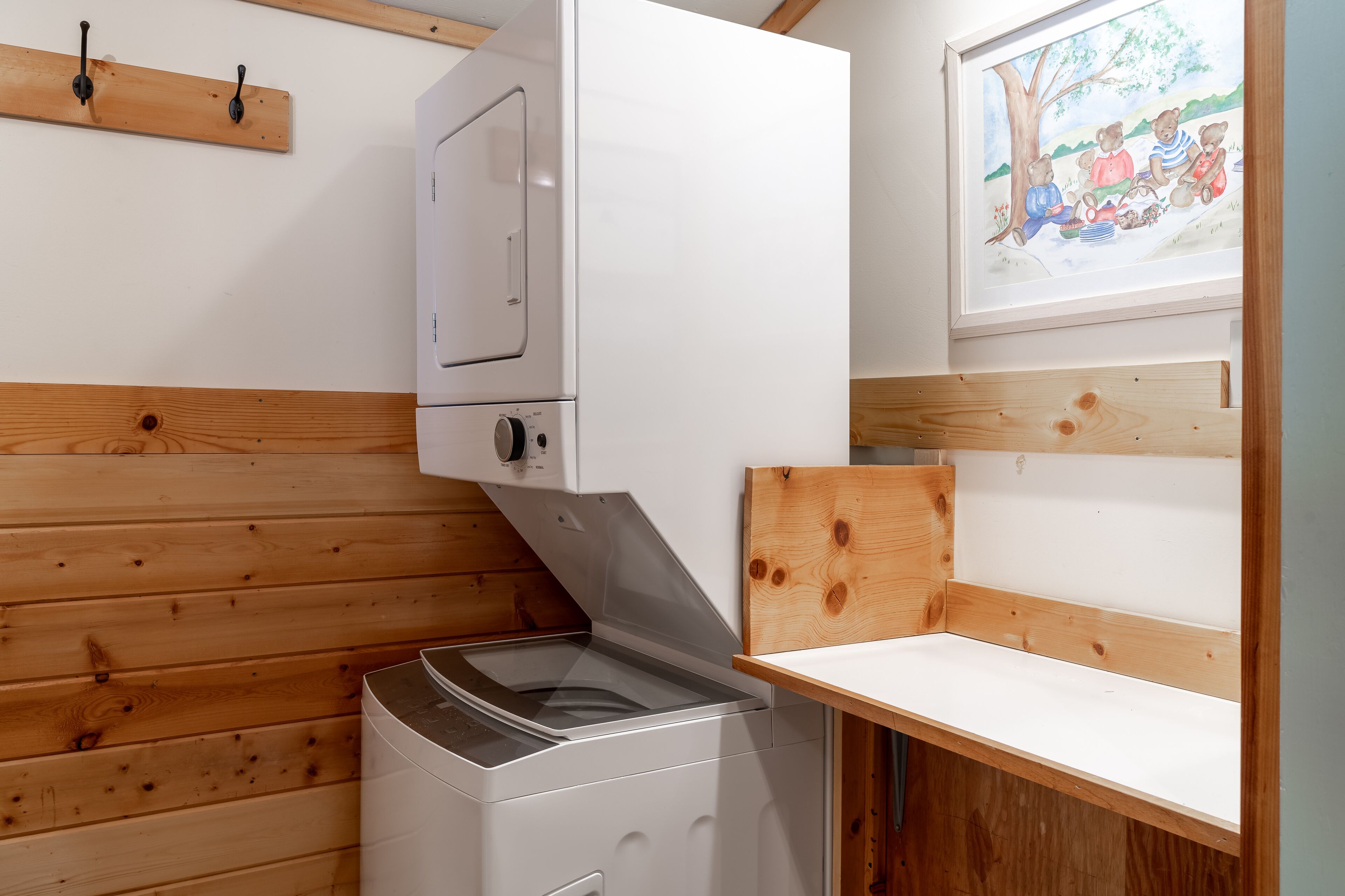 Une buanderie équipée d’un lave-linge, d’un étendoir et d’un banc en bois.