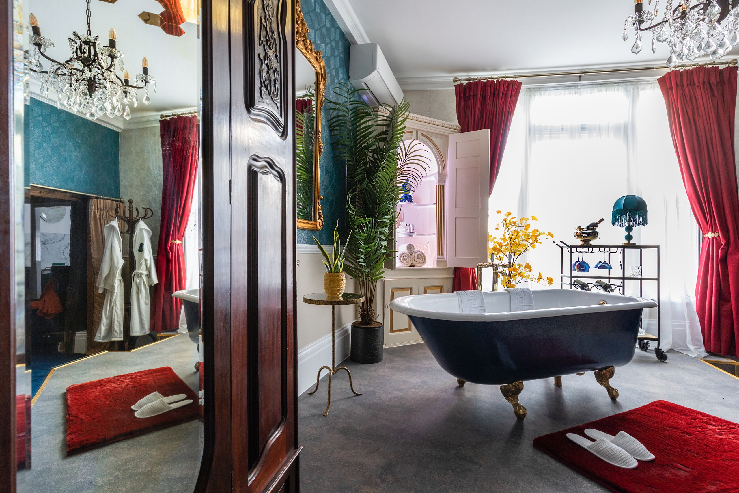 Ein Badezimmer mit einer freistehenden Badewanne, einem großen Spiegel und einem Kronleuchter.