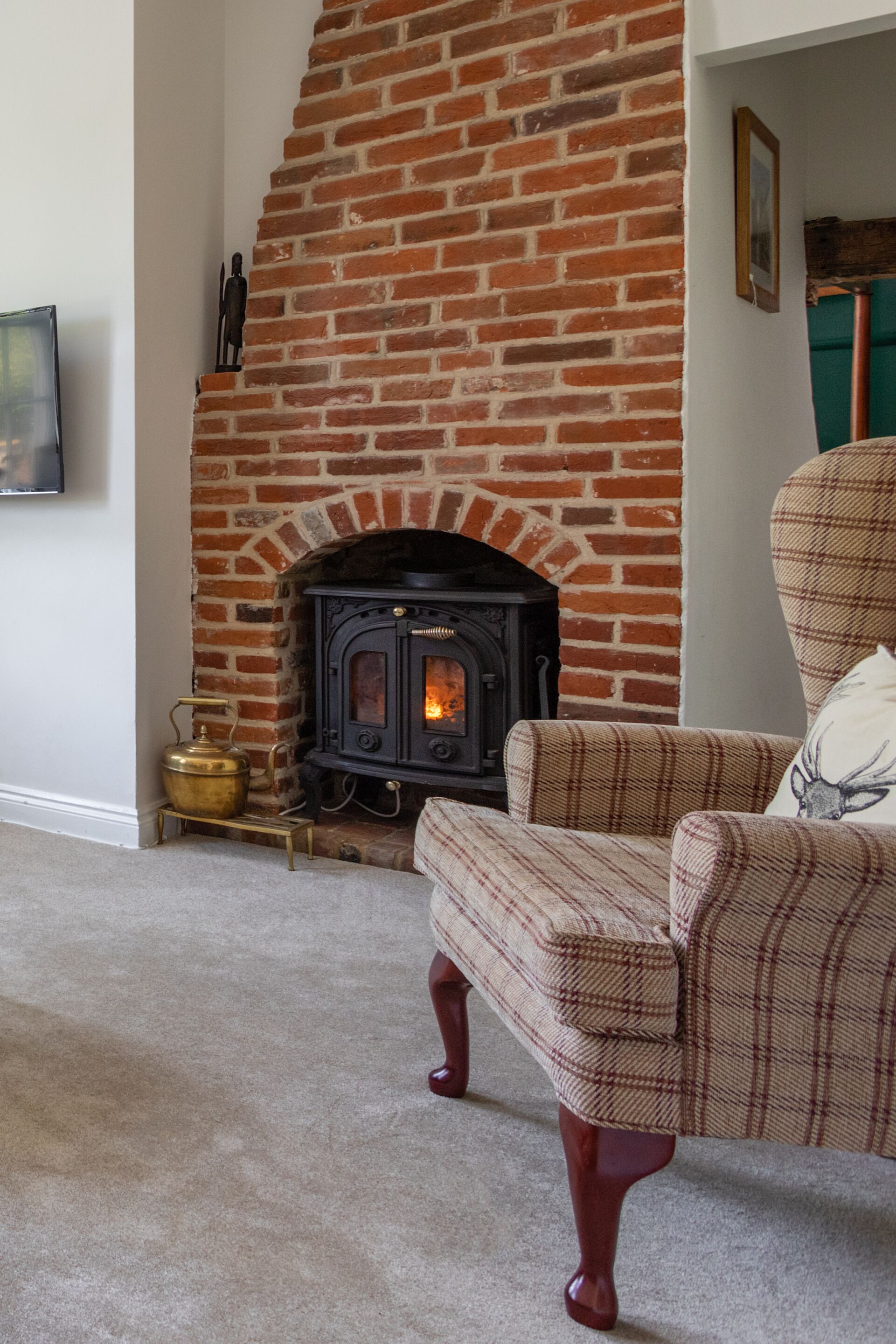 A living room with a brick fireplace, a sofa, and a small brass kettle.