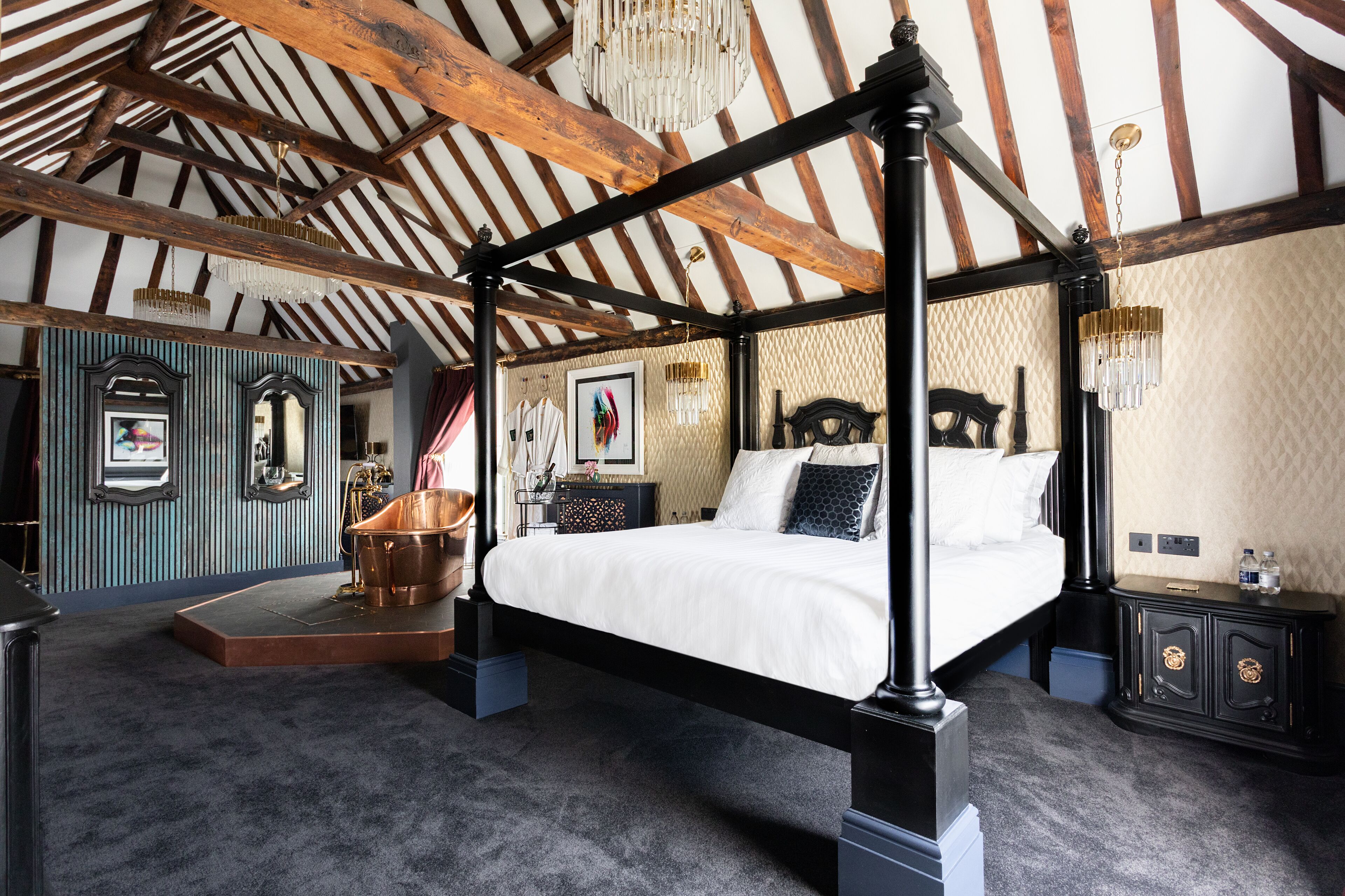 A four-poster bed in a room with exposed wooden beams and a chandelier.