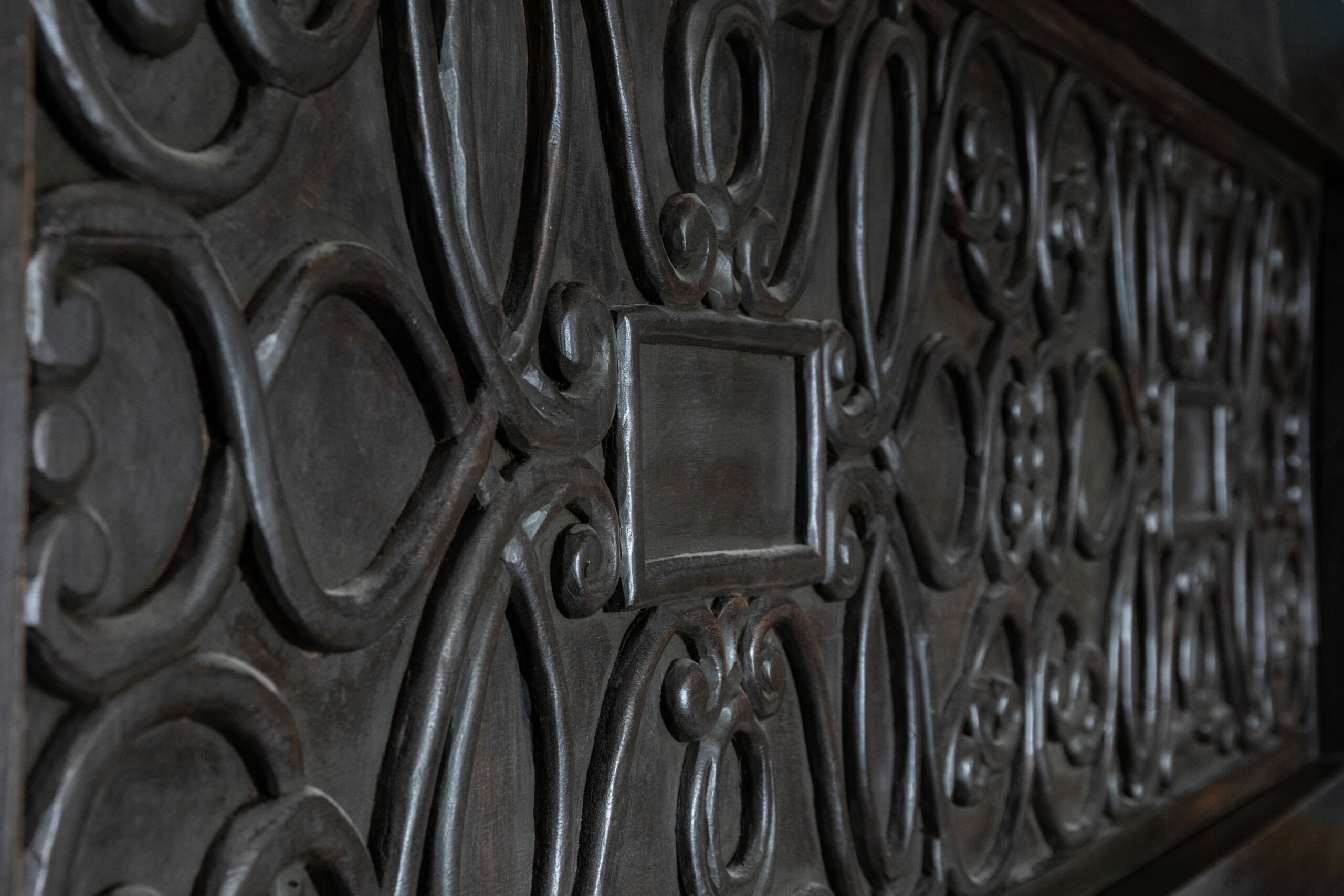 Un motif travaillé en métal, caractérisé par des ornements complexes et un élément rectangulaire central.
