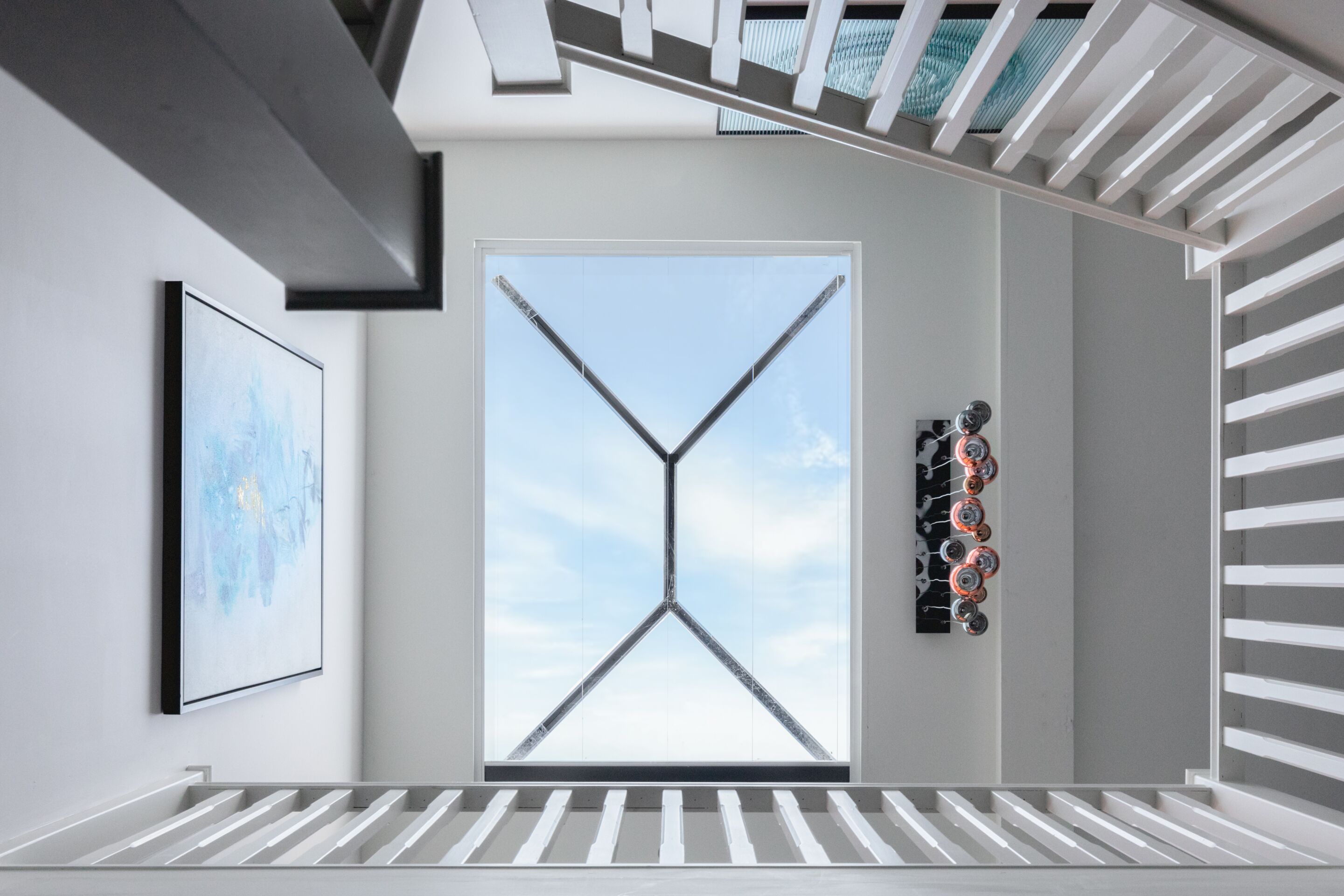 A modern interior with a large window, a framed artwork, and a unique wall decoration.