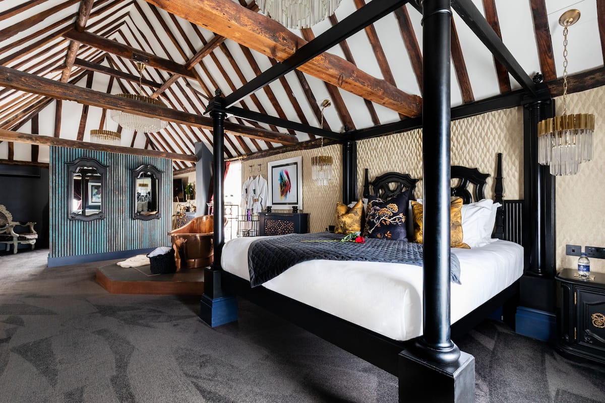 A four-poster bed with a black frame, a white bedspread, and decorative pillows.