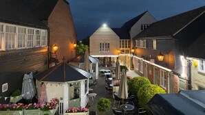Un pati amb seients exteriors, una glorieta i una filera d'edificis amb finestres il·luminades.
