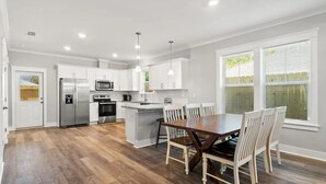A modern kitchen with white cabinets, stainless steel appliances, and a central island with seating.
