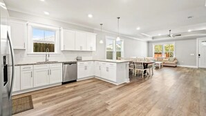 A spacious kitchen with white cabinets, a dishwasher, and a dining area with a table and chairs.