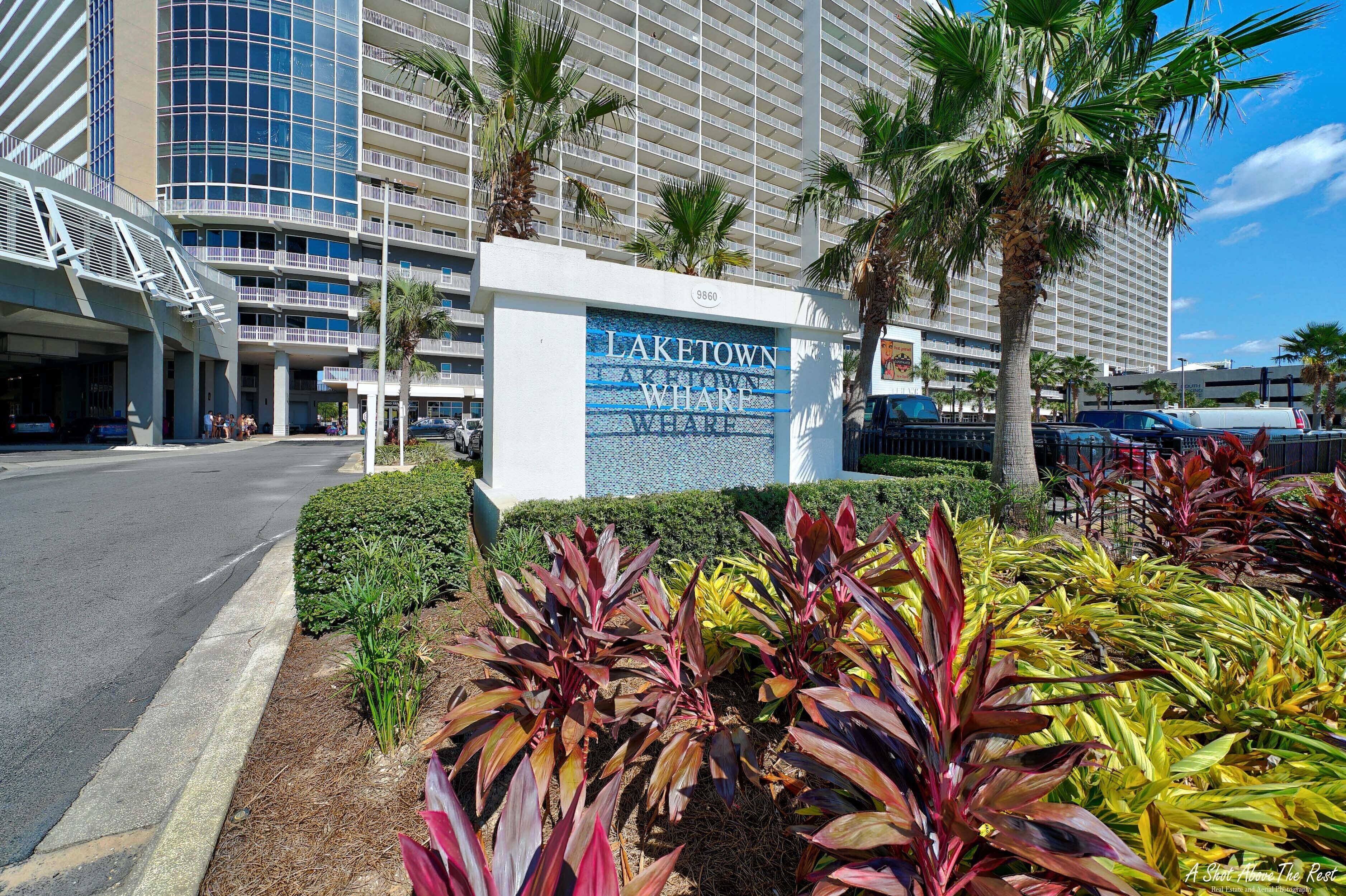 A hotel sign with 'LAKE TOWN' and 'WHALE' visible, surrounded by palm trees and a parking area.