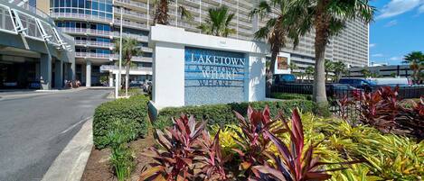 A hotel sign with 'LAKE TOWN' and 'WHALE' visible, surrounded by palm trees and a parking area.