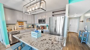 A modern kitchen with granite countertops, stainless steel appliances, and a central island with bar stools.
